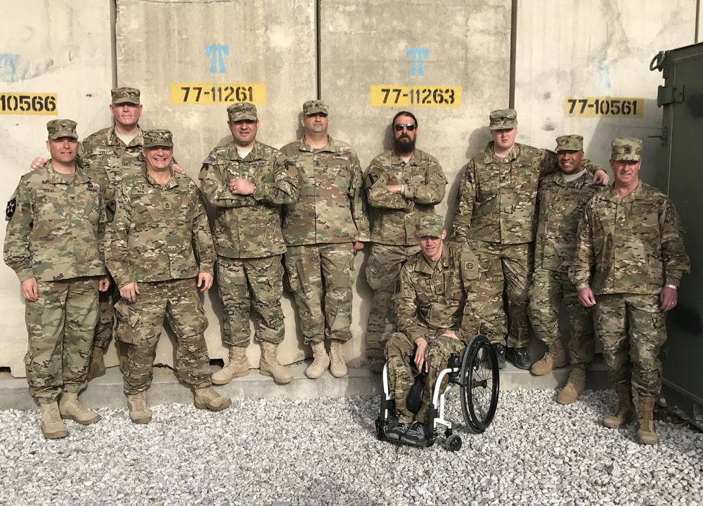 Military servicemen wearing camo and standing posed for a group photo. 